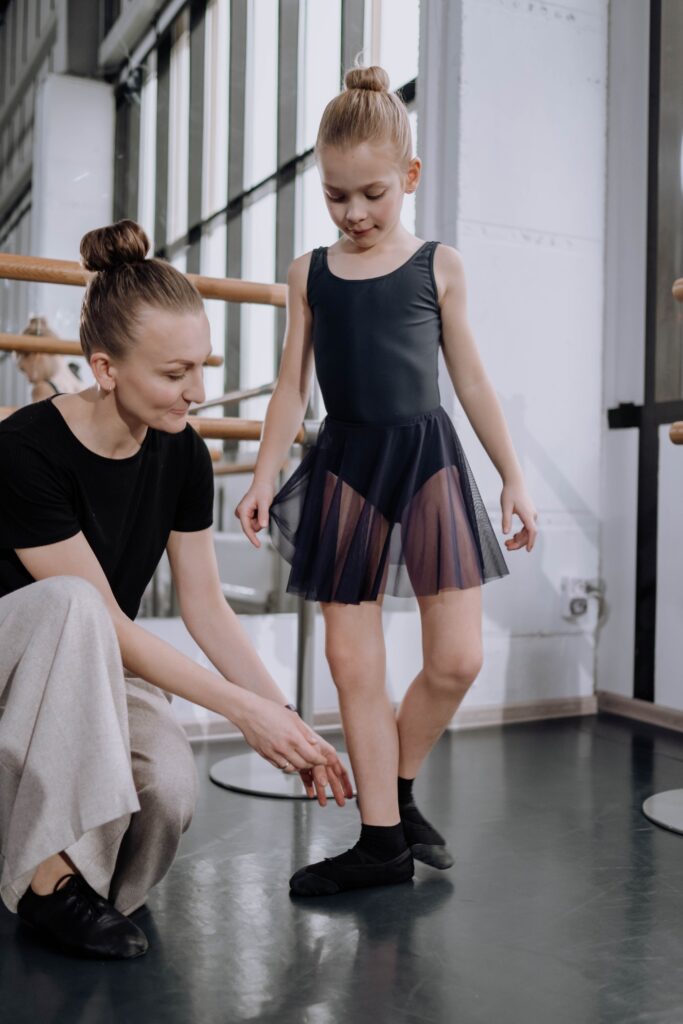 A ballet instructor gracefully demonstrating a pirouette, while attentive students observe in a well-lit studio with polished floors.